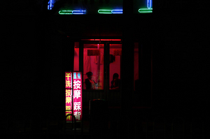 Two girls sit near the window of a massage salon on a street in the city of Weifang in Shandong Province